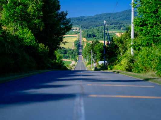 Scenic winding country road through green rolling hills.