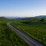 Akiyoshidai meadows, winding road, distant mountain landscape.