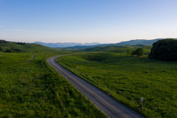 Akiyoshidai meadows, winding road, distant mountain landscape.