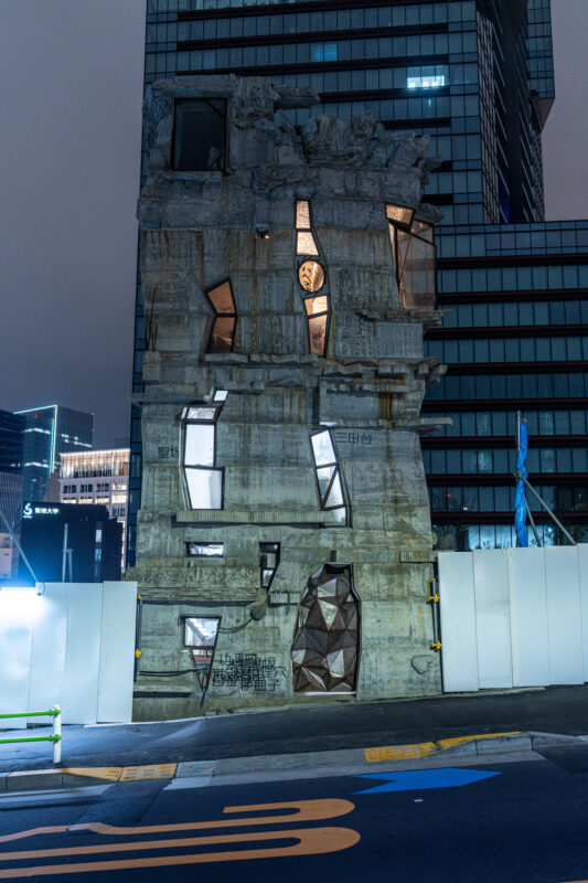 Arimasutonbiru brutalist concrete tower with glowing jagged windows at night in Tokyo