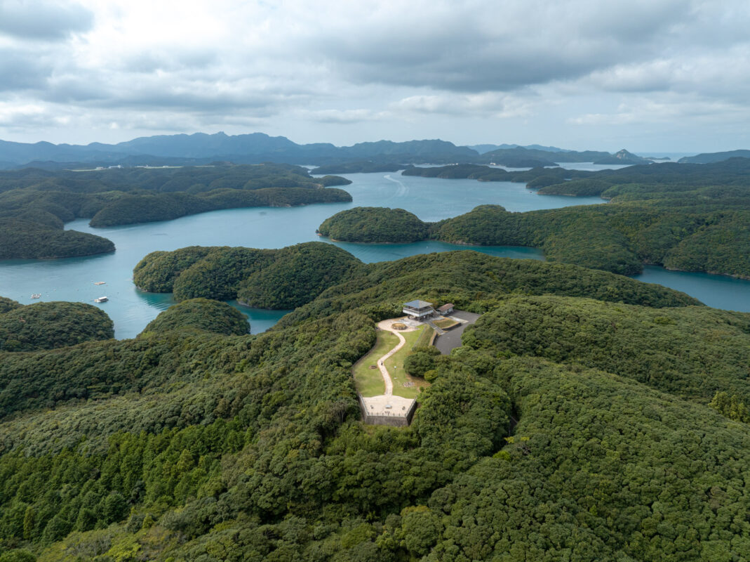 Aerial view from Manzeki Observation Deck of forested islands and turquoise coastline in Japan.