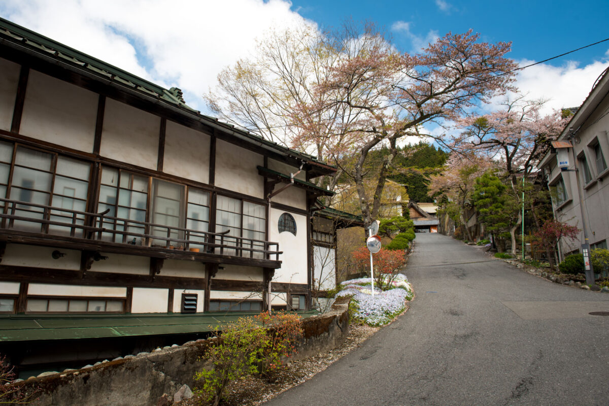 Sekizenkan Ryokan beside a quiet mountain road with cherry blossoms under blue sky