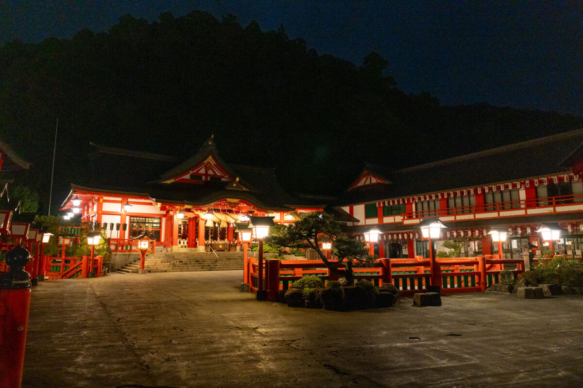 Lantern-lit Taikodani Inari-jinja Shrine at night with vermilion buildings and stone courtyard