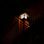 Glowing lantern along vermilion torii gates at Taikodani Inari-jinja Shrine at night.