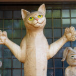 Wooden cat sculpture with raised paws at Unrin-ji Temple entrance in Japan