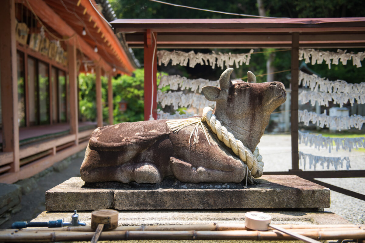 Stone ox statue with shimenawa and omikuji at Wakaura Tenmangu Shrine, Wakayama, Japan.