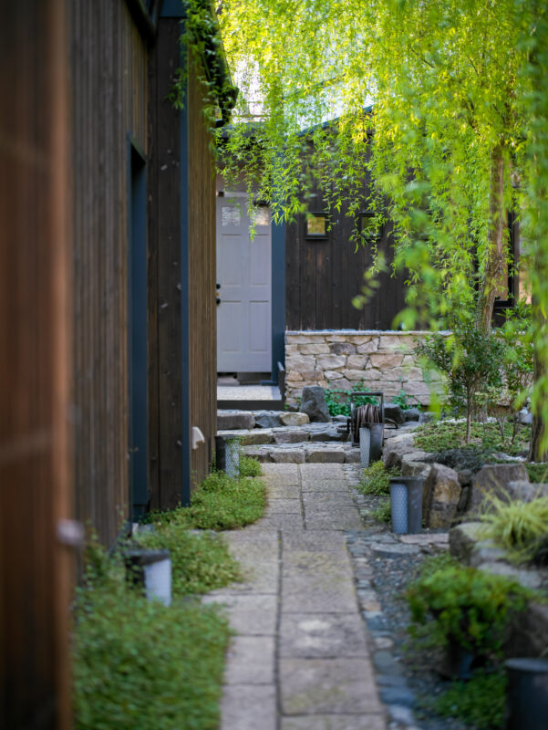 Quiet stone alley in Kyoto Gion district with wooden walls and lush greenery