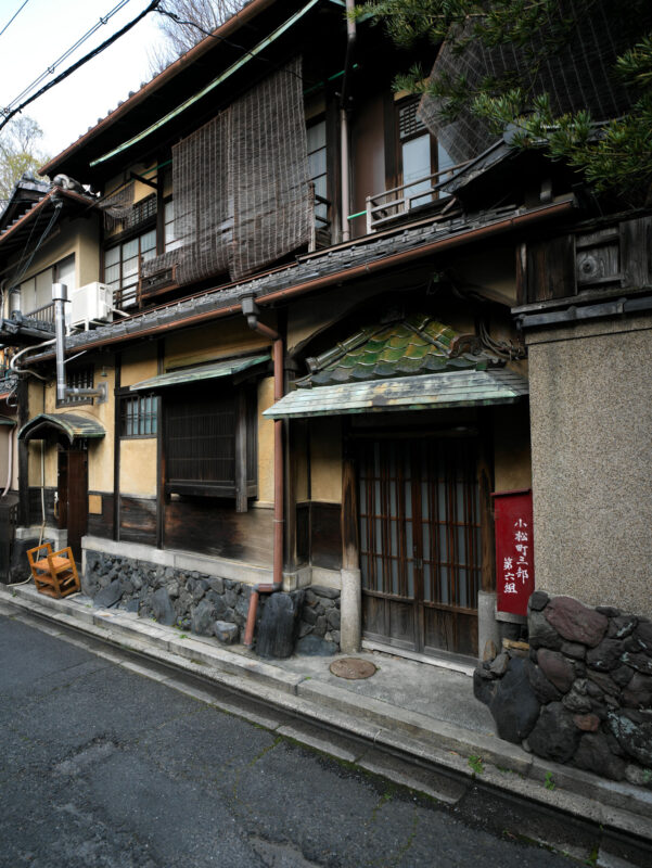 Quiet Gion street in Kyoto with traditional machiya townhouse and red Japanese sign.