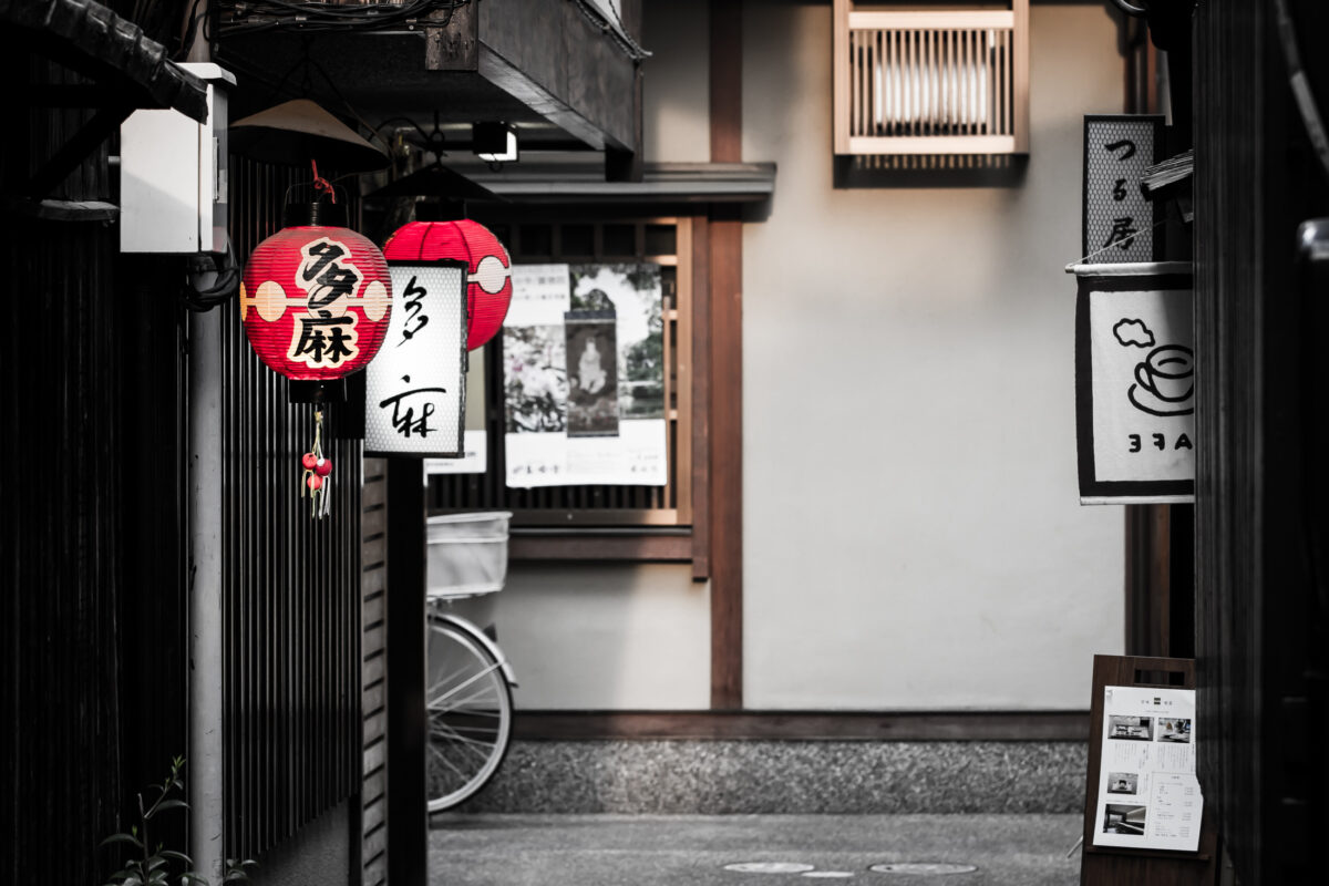 Quiet Japanese alley with red paper lanterns, wooden storefronts, and café signage