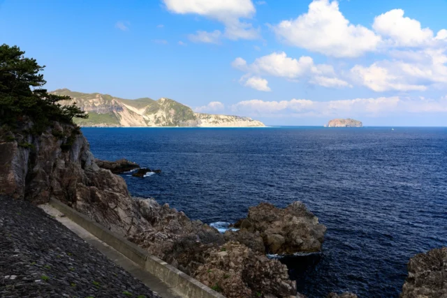 Lush cliffs guard the sea, Deep blues kiss rocky outcrops, Isle whispers secrets.豊かな崖 青海と岩を抱く 島が囁く#offbeatjapan #hiddenjapan #coastallandscape #naturephotography #japan #serenebeauty #wanderlust