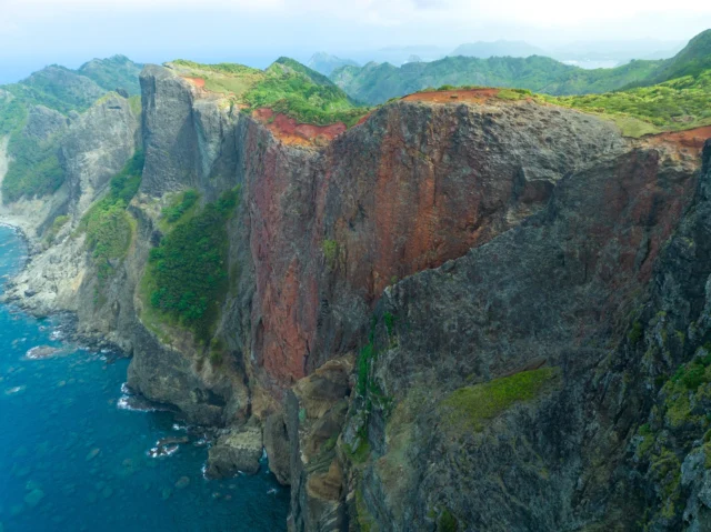 Rust cliffs kiss the sea, Turquoise whispers secrets deep— Nature's vivid brush. 崖が海と キスをしながら蒼き 自然の筆。 #offbeatjapan #japan #coastallandscapes #volcanicisland #naturelovers #stunningviews #wanderlust #cliffside
