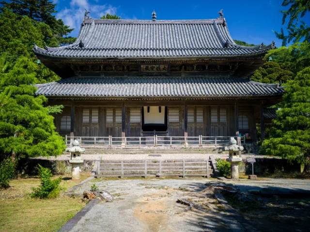 Pines whisper secrets, Under curved tiles and clear skies, Stone lanterns in peace. 松が囁き 曲がる瓦の下、 石灯籠、静かに。 #offbeatjapan #japan #traditionandnature #dojospirit #japanesearchitecture #peacefulplaces #serenesettings
