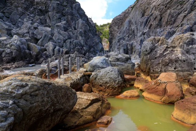 Rust and gray mingle, Path of ropes winds through the cliffs— Emerald pools gleam.---錆と灰混じる、 崖間綱道行く— 翡翠の池輝く。 ---#offbeatjapan #japan #abandonedbeauty #ruggedlandscapes #hiddenjapan #volcanicbeauty #naturelovers